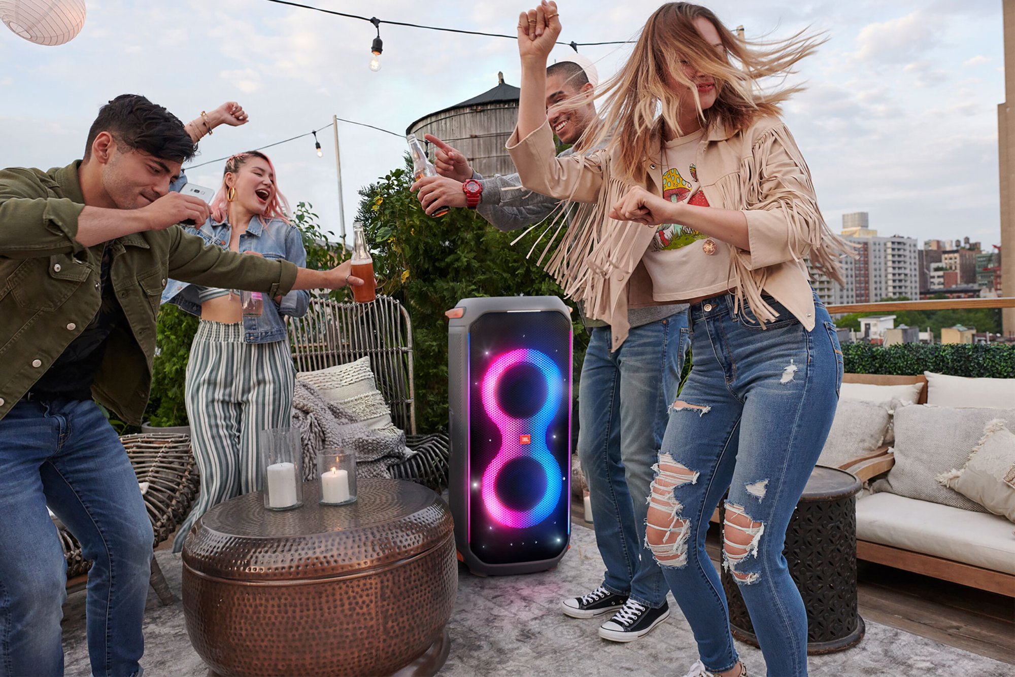 Friends dancing around a JBL PartyBox at a terrace party